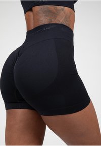 Zwarte sportshorts met een gevoerde tailleband en een figuuraccentuerend ontwerp. Bevat naadloze stiksels en een gladde afwerking.