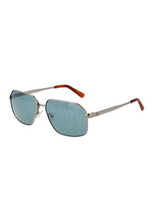 Occhiali da sole con sottile montatura in metallo argentato, lenti blu con motivo geometrico e sottili aste marroni inclinate verso l'esterno.