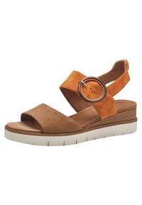 Sandalo in suede color tan e arancio con punta aperta, una fascia anteriore ampia, un accento circolare e una suola piatta bianca e testurizzata.
