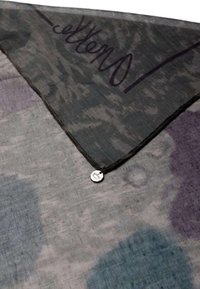 Bufanda ligera en gris con patrones abstractos en púrpura y azul. Presenta una etiqueta de logo en plata y un tejido suave y texturizado.