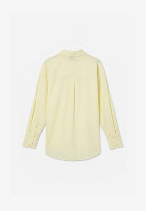 Hosszú ujjú, halványsárga ing gombos mandzsettákkal, hátsó nyereggel és középső redővel, hátulról fehér háttéren bemutatva.