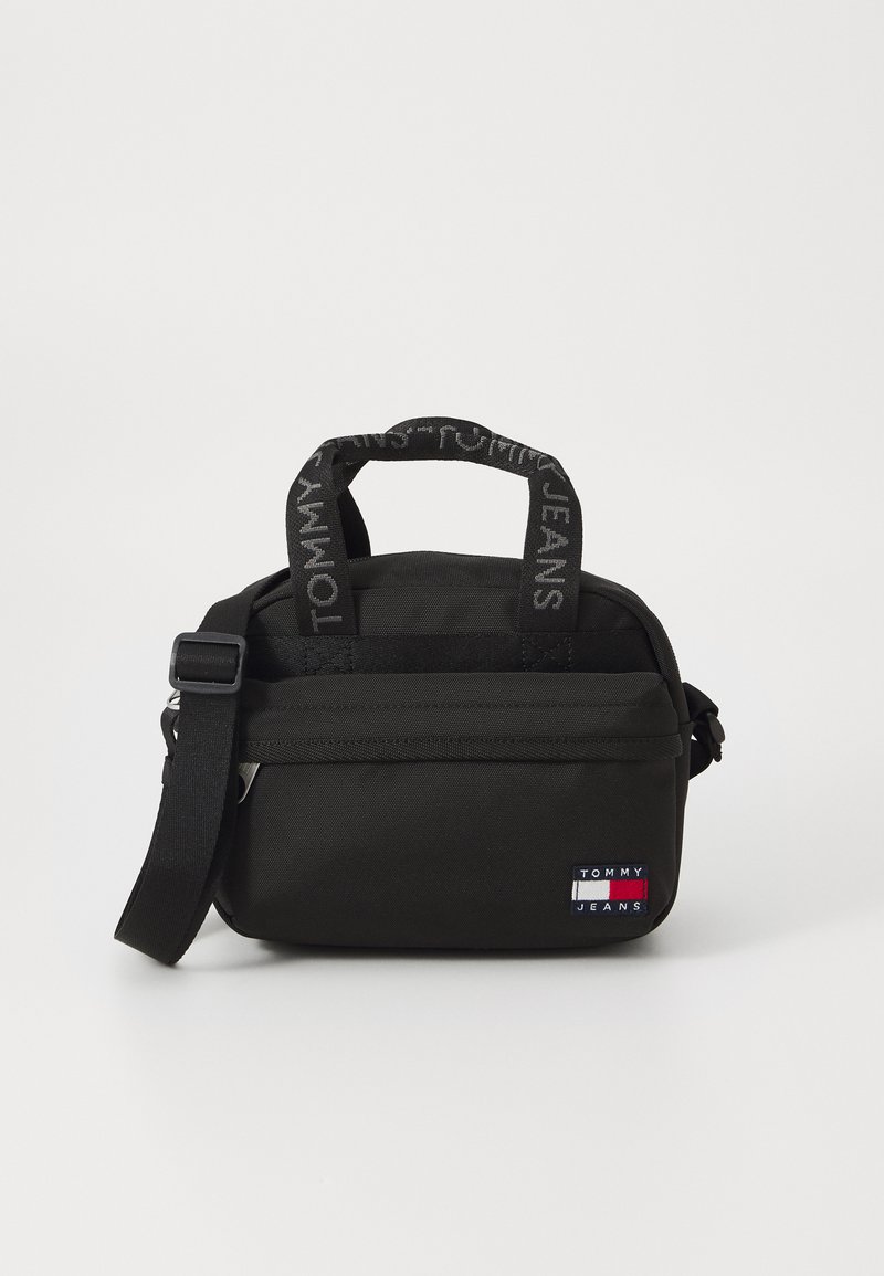 Fekete szövet vászontáska rövid fogantyúkkal és levehető vállpánttal. Háromszög alakú logófelvarróval és texturált részletekkel a pántokon.