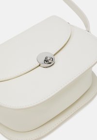 Borsa a tracolla in pelle bianca, con una forma arrotondata, caratterizzata da una chiusura circolare in argento, dettagli di cuciture sottili e una superficie liscia.