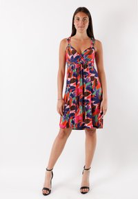 Vartalon mukaisesti muotoiltu, värikäs hihaton mekko, jossa on v-pääntie. Mekossa on lehtikuvio punaisena, vihreänä ja sinisenä. Mekkoa korostavat olkaimet ja sen virtaava muotoilu.