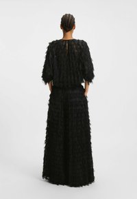 Completo di due pezzi nero con un design testurizzato simile a piume, composto da una maglietta ampia e pantaloni a gamba larga, entrambi con una finitura morbida.