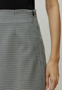 Houndstooth-patroon rok in marineblauw, lichtblauw en beige. Heeft een hoge taille met een zijrits en een aansluitende silhouet.
