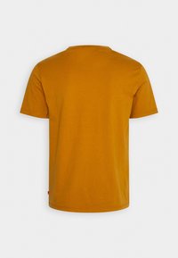 Musztardowożółta koszulka z krótkim rękawem, wykonana z bawełny, z okrągłym dekoltem i prostym krojem, z gładkim tyłem.