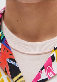 Hemd mit Kragen aus einem bunten, gemusterten Stoff mit geometrischen Designs; pinker gerippter Ausschnitt; weiche, glatte Textur.