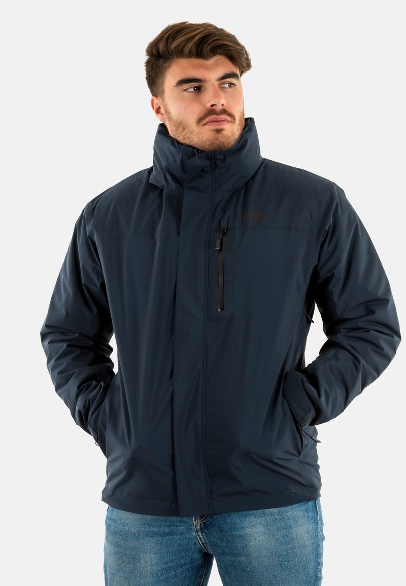 Veste isolée bleu marine avec col montant, poche zippée et poches latérales. Fabriquée en tissu léger, présentant une texture lisse et un design adapté à l'extérieur.