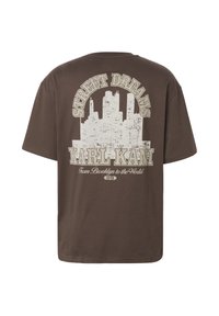 T-shirt marron avec un graphique de skyline de ville blanche et un texte indiquant "Street Dreams", "Karl Kani" et "De Brooklyn au Monde" au dos.