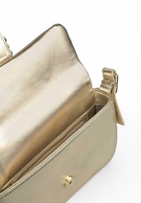 Bolso de mano metálico dorado con una textura suave, que cuenta con un bolsillo interior con cremallera y un cierre a presión magnético. Incluye una correa ajustable.
