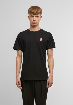 Camiseta de algodón negra con mangas cortas y un cuello redondo, que presenta un pequeño logotipo gráfico en rojo y blanco en el pecho.