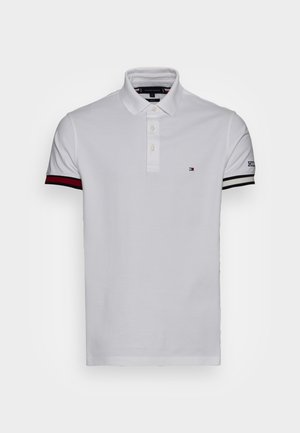 Polo blanc en coton avec un col à trois boutons, accents rayés rouges et noirs contrastants sur les manches, et logo sur la poitrine.