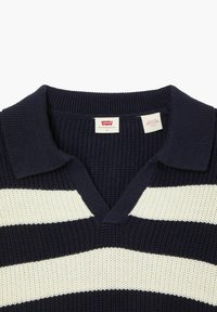 Mørkeblå strikket pullover med hvide vandrette striber, med V-hals og en struktureret stof. Indeholder et mærketikette ved kraven.