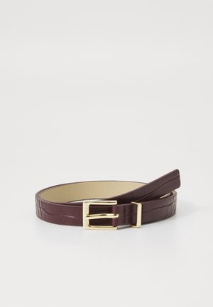 Ceinture en cuir marron à motif crocodile avec boucle rectangulaire dorée, roulée sur une surface blanche et plate.