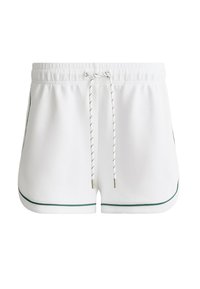 Shorts de sport blancs avec ceinture élastique, cordon noir et blanc, et passepoil vert le long des bords, vus de face.