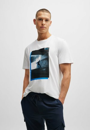 Witte katoenen t-shirt met een blauw en zwart grafisch print van een skater. Ronde halslijn, korte mouwen, relaxte pasvorm.