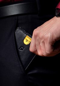 Black leather wallet partially visible in a pocket, with a golden card peeking out. Fabric appears smooth with a slight sheen.