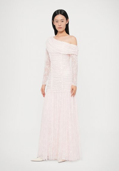 Długa różowa sukienka wieczorowa z marszczonym dekoltem, odkrytymi ramionami i przezroczystymi rękawami z koronki. Spódnica ma warstwową, falującą fakturę.