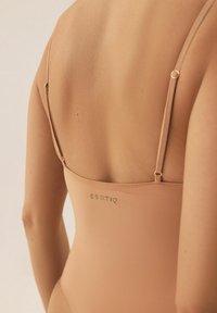 Nude kostium kąpielowy z cienkimi regulowanymi ramiączkami; gładka tekstura z subtelnym połyskiem; logo "ESOTIQ" w zieleni na plecach.