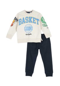 Felpa crema con grafica testuale blu e verde, disegni di basket, abbinata a pantaloni jogger navy con vita elasticizzata.