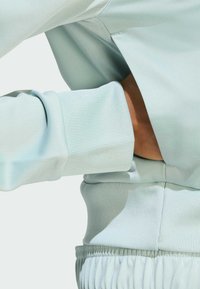 Light green, ribbed sweatshirt with a relaxed fit. Features a textured cuff and waistband, highlighting the soft, stretchy fabric.