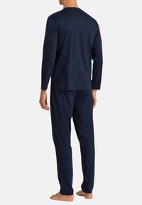 Tummansininen pitkähihaoinen paita ja siihen sopivat housut, jotka on valmistettu pehmeästä kankaasta. Vaatekokonaisuus on rento ja siinä on vähän yksityiskohtia selässä.