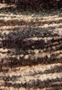Gros plan d'un tissu en laine à texture bouclée avec des rayures mélangées marron, beige et grises.
