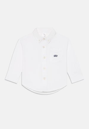 Chemise à manches longues blanche pour tout-petits avec col boutonné, boutons sur le devant, poche poitrine et logo "GAP" brodé en bleu marine.