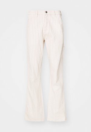 Cream-colored flared pants with vertical red pinstripes, featuring a button closure, side pockets, and a smooth textured fabric.