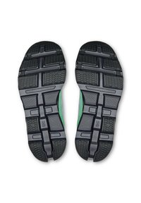 Black rubber sneaker soles with textured grip patterns and green accents along the sides, featuring a segmented design for flexibility.