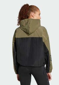 Hooded windbreaker jacket, olive green and black color block design. Made of lightweight, textured fabric with elastic cuffs and adjustable hem.