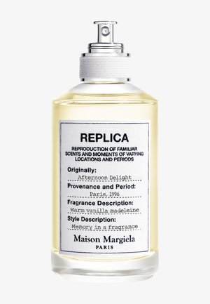 Duidelijke glazen parfumfles met het label Replica Afternoon Delight van Maison Margiela, met zilveren spraydop en lichtgele vloeistof erin.
