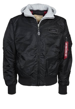 Veste bomber noire avec capuche grise, fermeture éclair à l'avant, poches zippées, poignets et ourlet côtelés, et étiquette rouge "Remove Before Flight" sur la poche de la manche gauche.