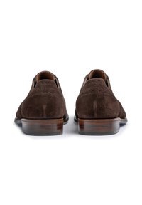 Scarpe in suede marrone con dettagli brogue, dotate di tacchi in legno e una finitura liscia e lucida. Il design è elegante, con una punta leggermente arrotondata.