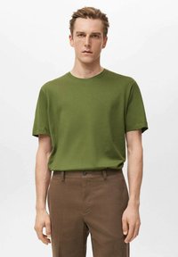 Zelené tričko s krátkym rukávom z m�äkkej tkaniny, s okrúhlym výstrihom. Kombinované s hnedými nohavicami so zapínaním na gombík.