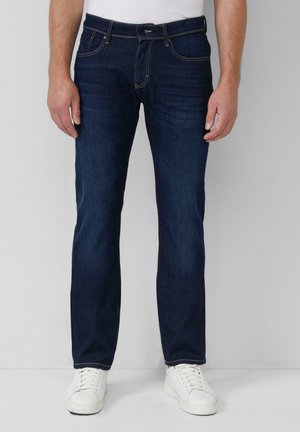Dark blue denim jeans with a straight-leg cut, five pockets, and contrasting yellow stitching. Paired with white sneakers.