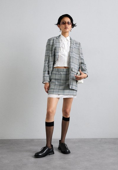 Plaid blazer and skirt set in blue and gray tones, paired with a white shirt. Black shoes and knee-high sheer socks complete the look.