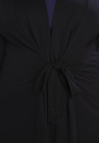 Indumento avvolgente nero con una coulisse in vita. Tessuto morbido ed elastico con una texture liscia e un design a profonda scollatura a V.