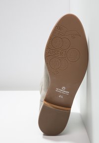 Semelle d'une chaussure en suède beige Peter Kaiser montrant des pièces embossées, le logo et la taille 4½ avec un patch texturé au talon.