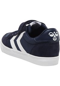 Marinblå sneakers med vita detaljer, tillverkade av canvas och mocka, med kardborreband och rundad tå. Har logotyp på hälen.