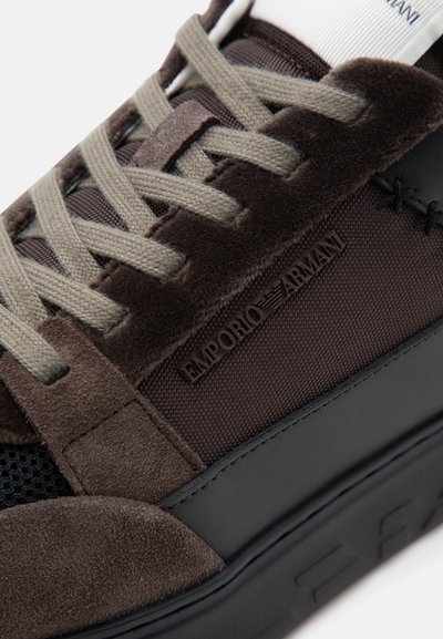 Κοντινό πλάνο καφέ sneaker Emporio Armani με υφές από σουέτ και δίχτυ, μπεζ κορδόνια και μαύρη ελαστική σόλα.