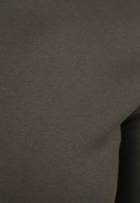 Donkergroene katoenstof met een gladde textuur, met een subtiele glans en een consistent oppervlakpatroon. Geen zichtbare versieringen of patronen.