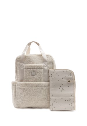 Beige zacht getextureerde vierkante rugzak met voorvak en crème verschoonmat met kleine hartjespatronen en drukknoopsluiting, leunend op de zijkant.