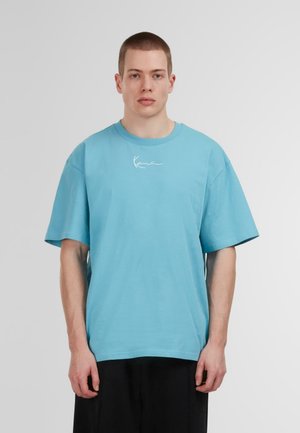 Helles blaues Oversized-T-Shirt aus Baumwolle mit kurzen Ärmeln und einem weißen Signaturdesign auf der Vorderseite.