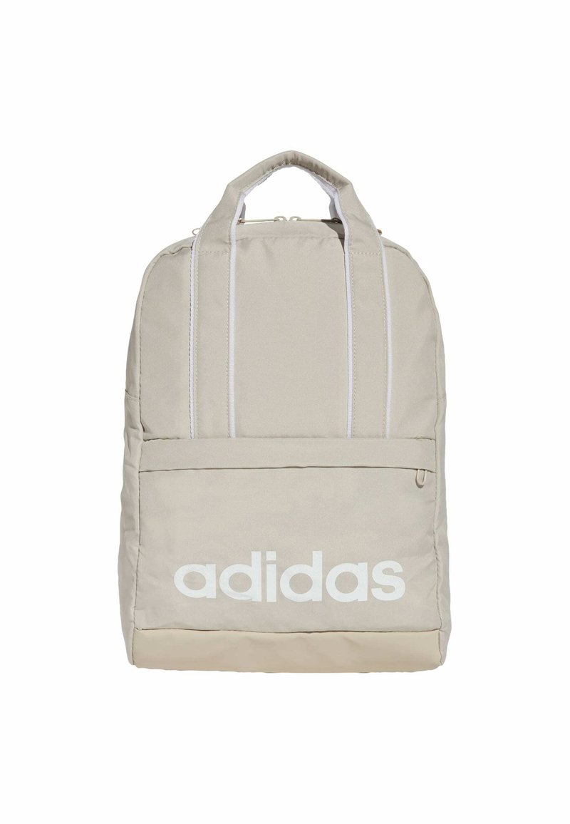 Mochila Adidas beige con una textura de tela suave, equipada con un gran bolsillo frontal y branding en blanco. Incluye dos correas de hombro acolchadas.