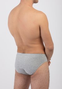 Slip in cotone grigio con elastico, design minimalista e texture liscia. L'immagine mette in evidenza il lato posteriore, evidenziando l'elastico e la vestibilità.