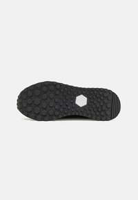 Black rubber shoe sole with hexagonal tread pattern, featuring a central hexagonal section and ridged edges for traction.