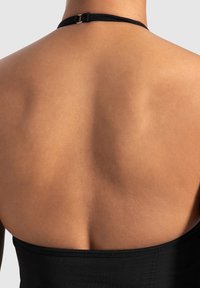 Czarny top na halter z gładką teksturą, o minimalistycznym designie i srebrnym zapięciu na szyi, widoczny z tyłu.