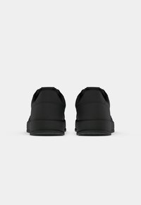 Pair of black athletic shoes shown from the rear on a plain white background.